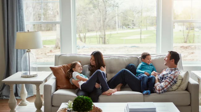 Family of four relaxing together on the sofa at home.