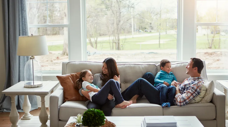 Family of four relaxing together on the sofa at home.
