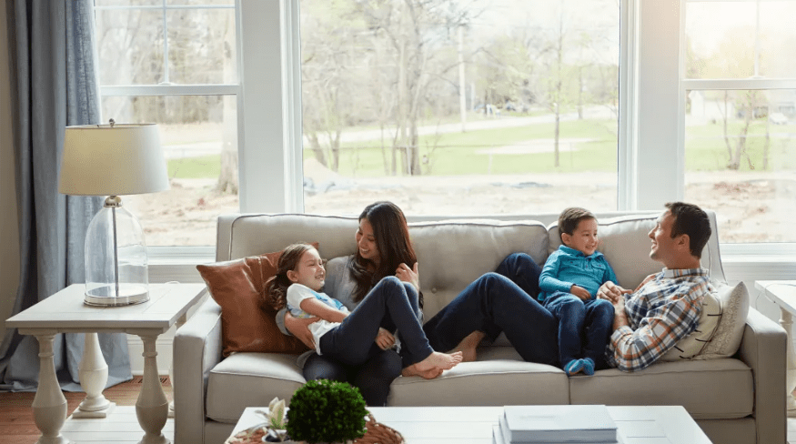 Family of four relaxing together on the sofa at home.
