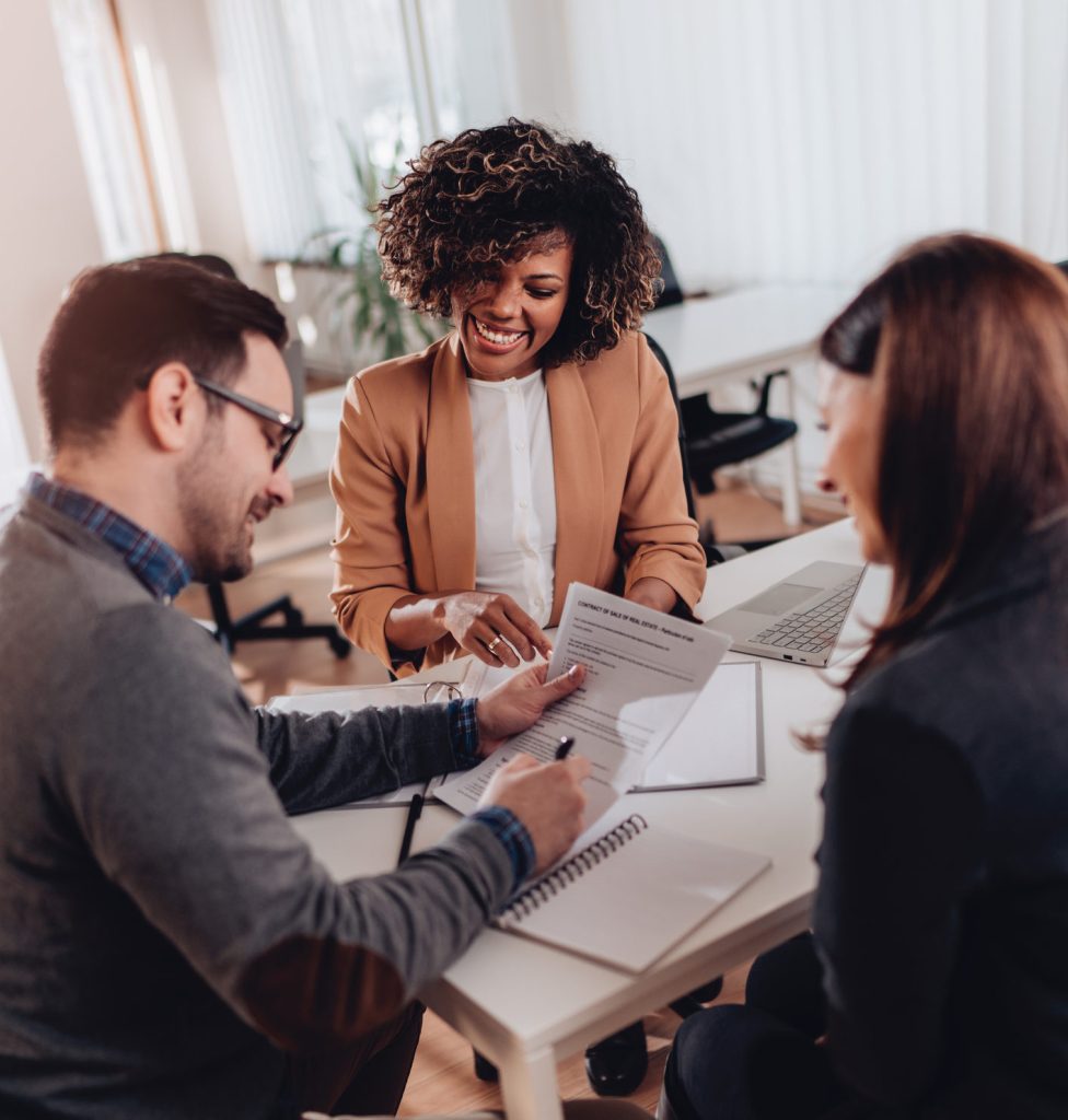 Couple sitting at the desk in the bank and signing loan agreement