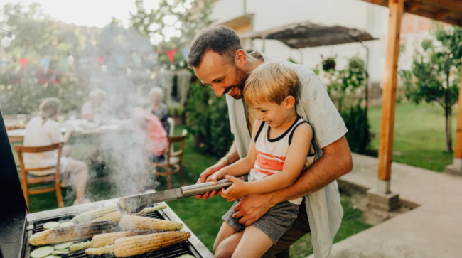 Dad showing his son how to grill.
