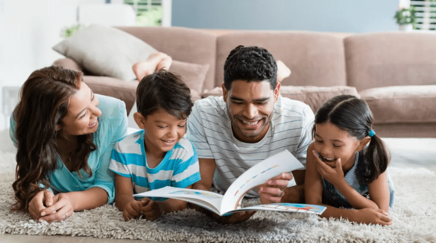 Family reading a book together in the living room.