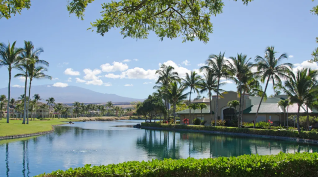Housing community surrounded by a lake with mountain views.