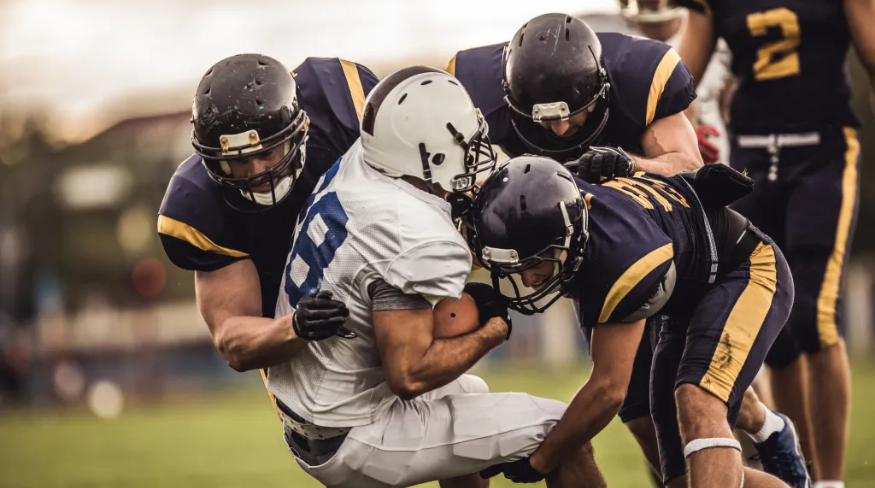 Football players tackling quarterback during a game.