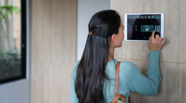 Woman entering pin to lock the door of her house using a home automation system.
