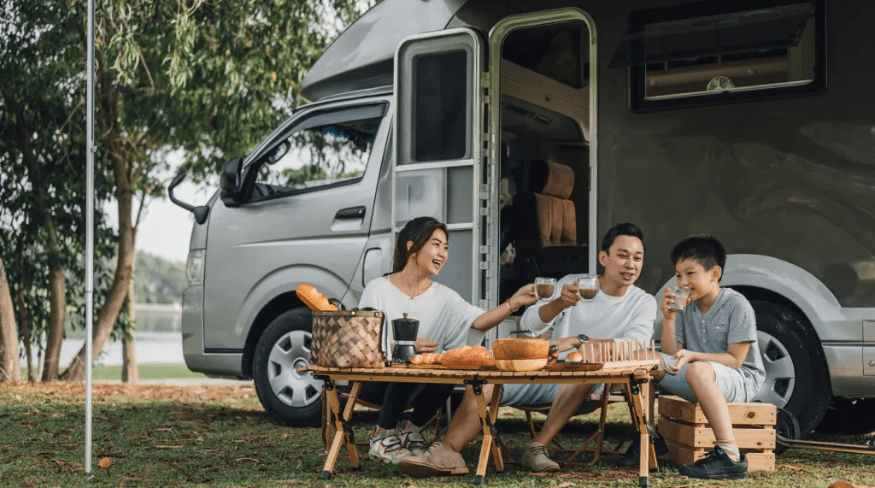 A family having a picnic outside a camper trailer.