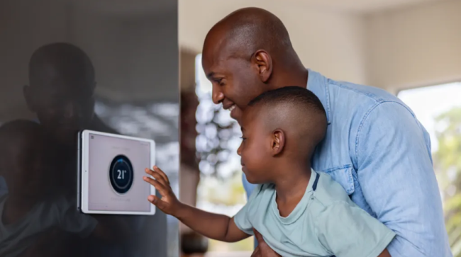Father and son using a home automation system to lower the temperature of their house.