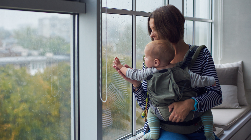 Mother and baby looking out side at the rain.